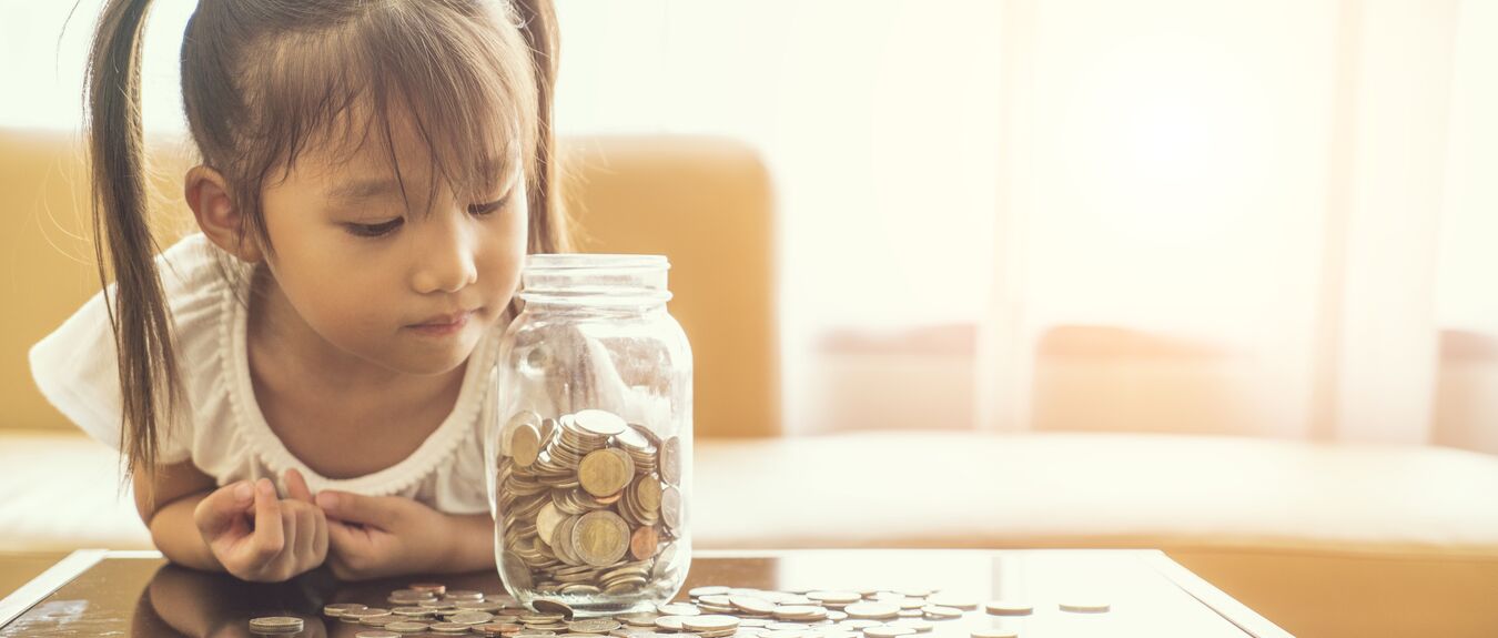 Little girl looking at jar of coins